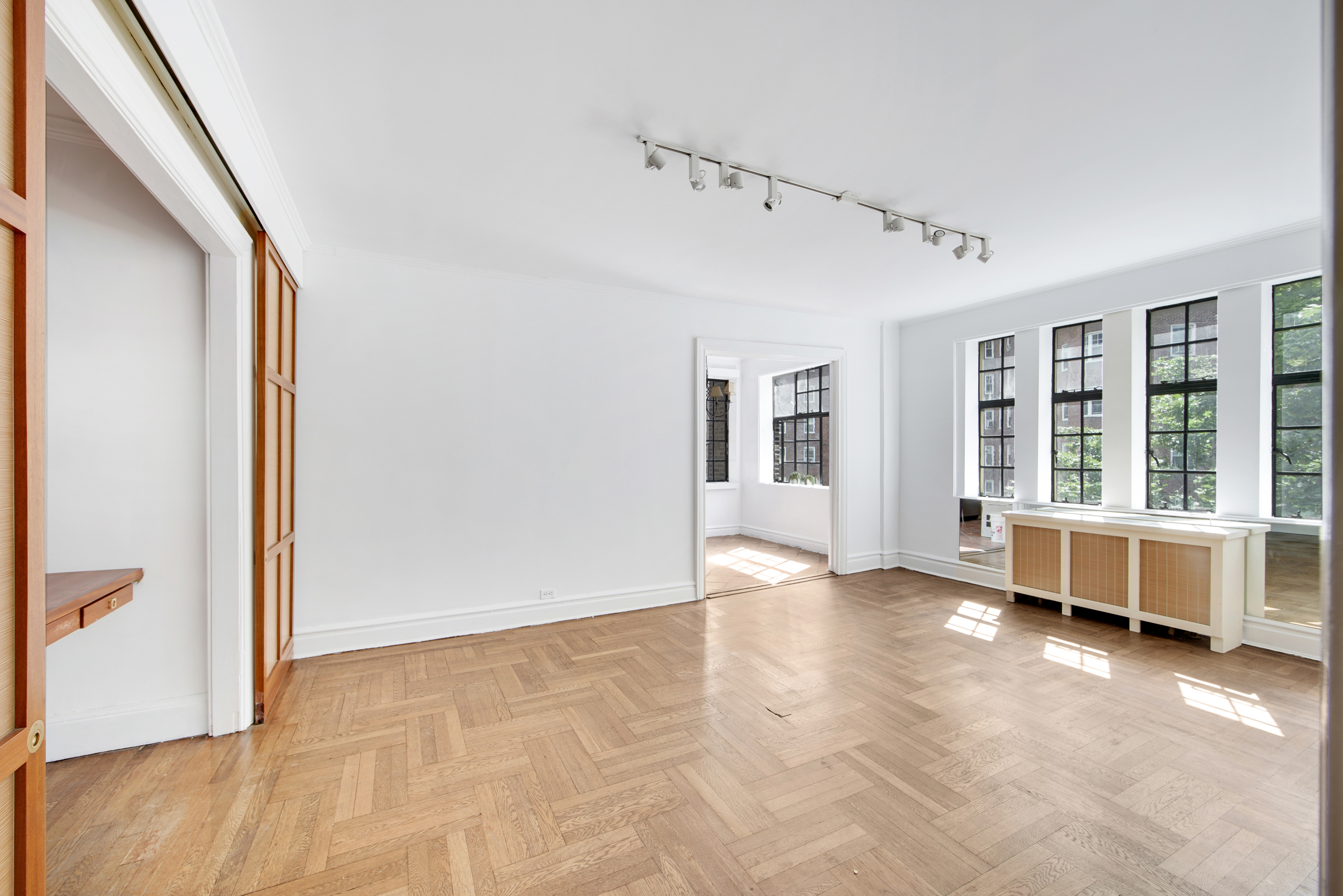 a view of an empty room with wooden floor and a window