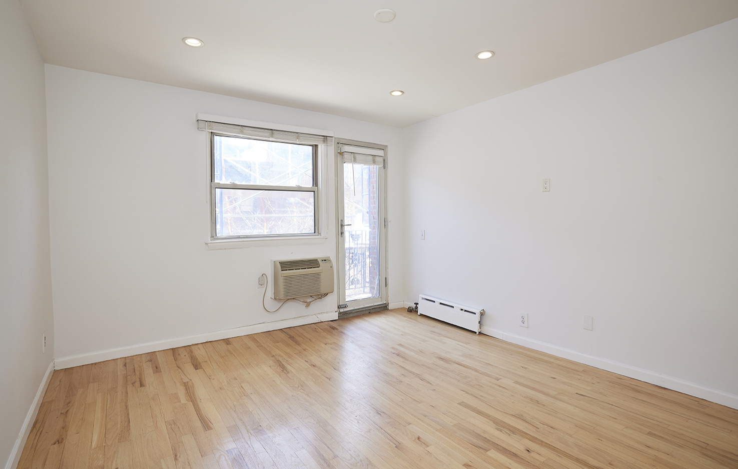 211 Thompson Street, Unit 5L Manhattan, NY 10012 - Photo 4 of 7 an empty room with wooden floor and windows