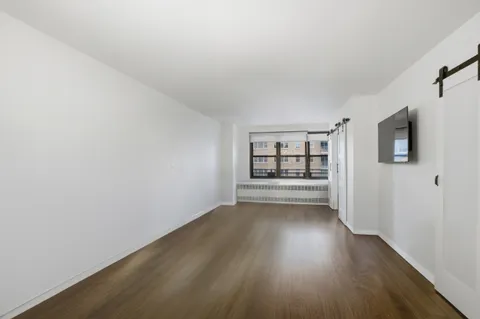 a view of an empty room with a window and wooden floor