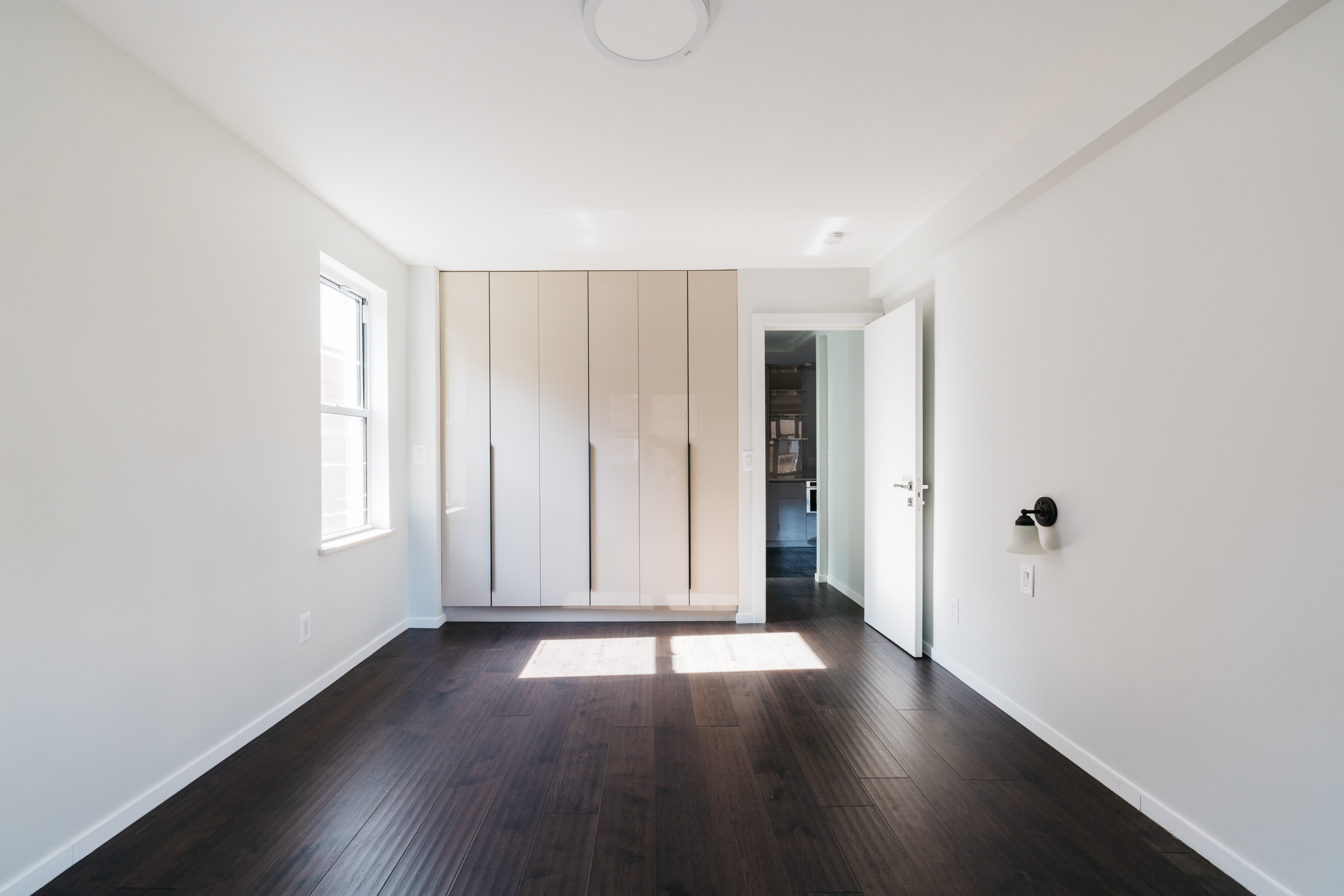 71-36 110th Street, Unit 4C Queens, NY 11375 - Photo 9 of 14 an empty room with wooden floor and windows