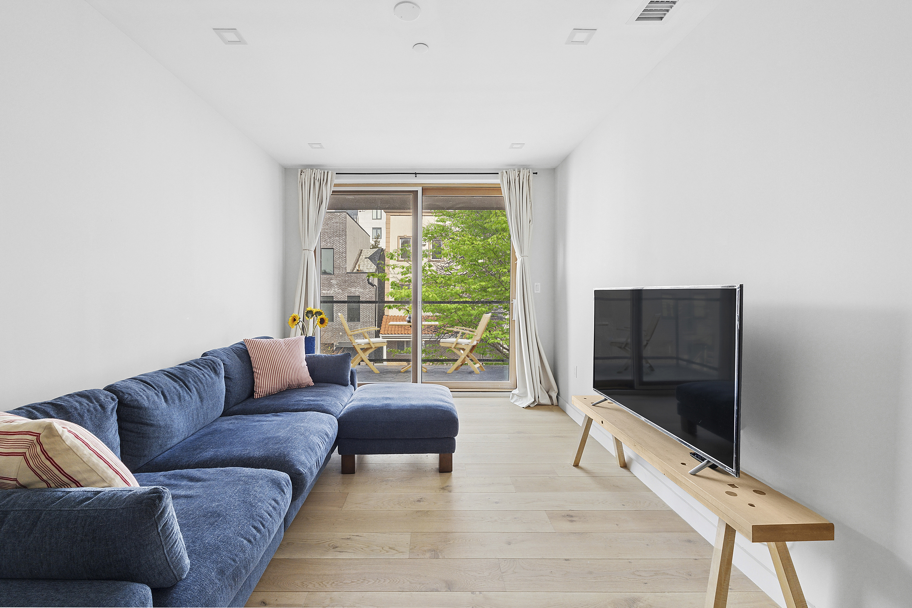 156 Devoe Street, Unit 3F Brooklyn, NY 11211 - Photo 2 of 9 a living room with furniture and a flat screen tv