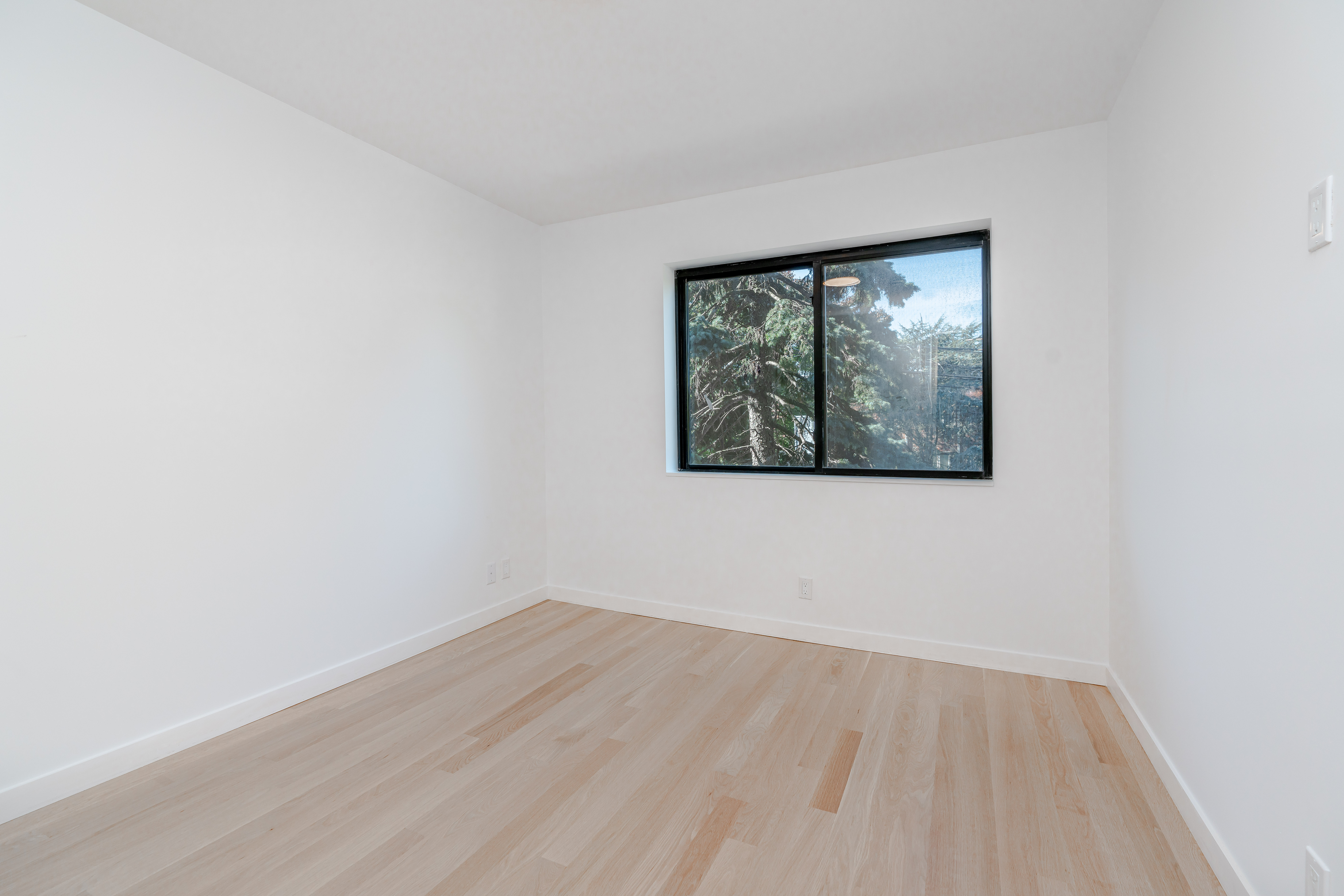 20-15 46th Street, Unit 2 Queens, NY 11105 - Photo 8 of 16 an empty room with wooden floor and windows