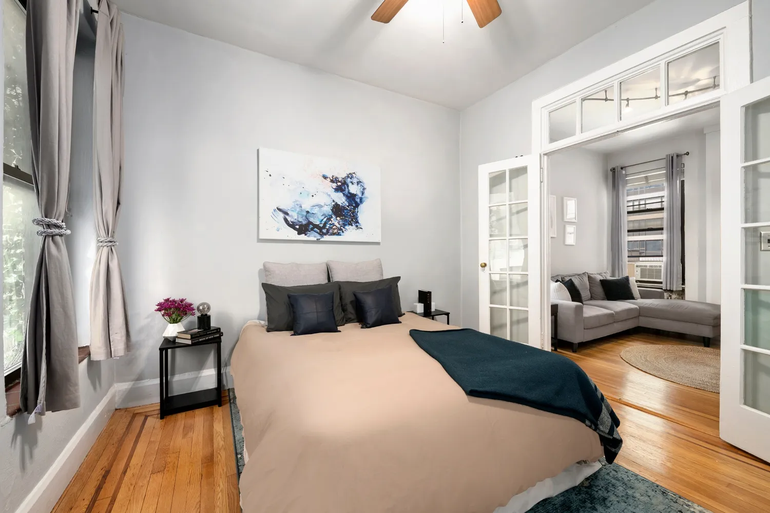 a bedroom with a bed a couch and a flat tv screen on dresser