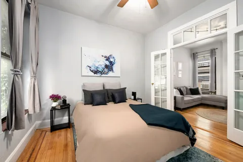 a bedroom with a bed a couch and a flat tv screen on dresser