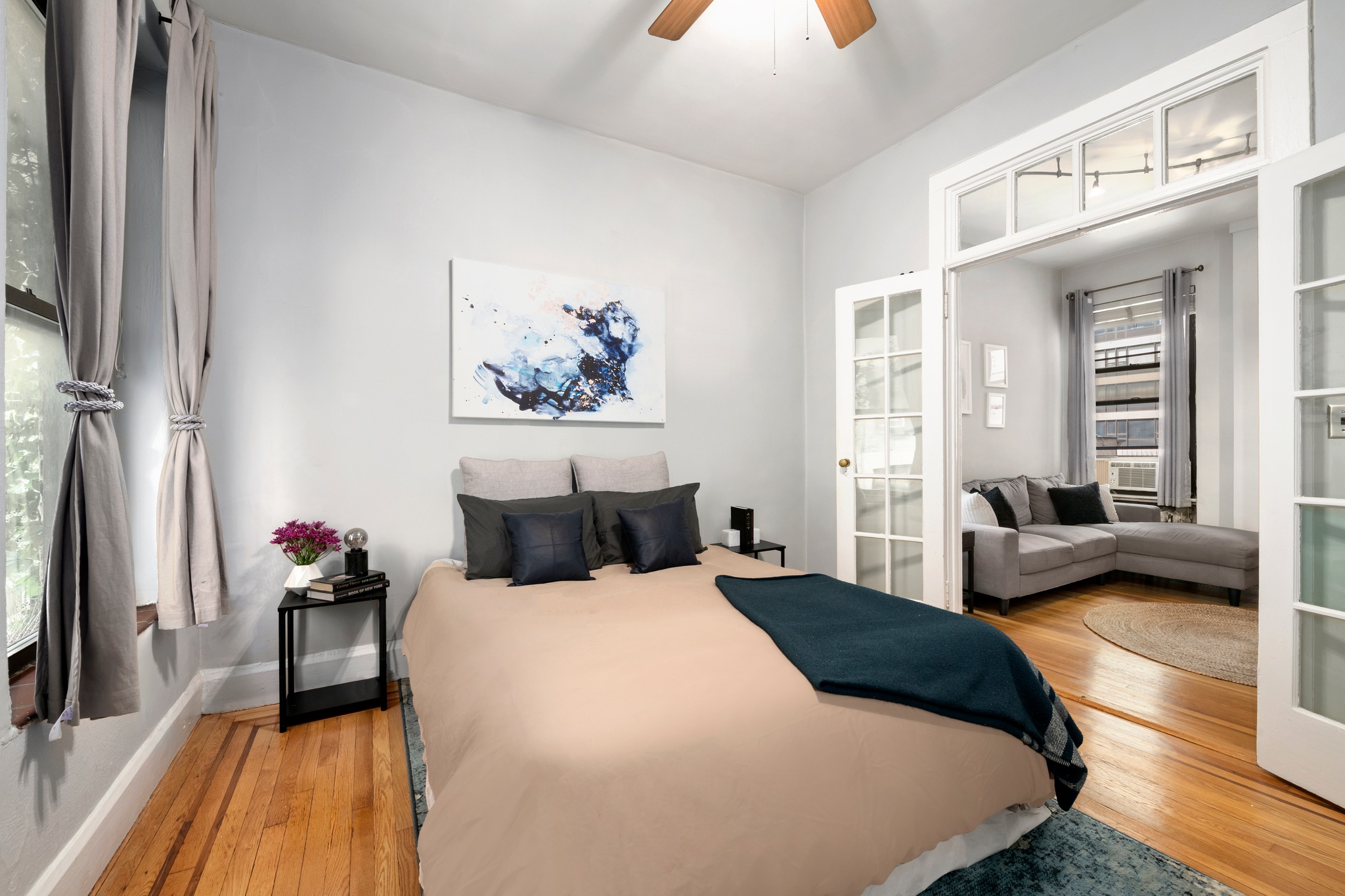 444 East 58th Street, Unit 6C Manhattan, NY 10022 - Photo 3 of 9 a bedroom with a bed a couch and a flat tv screen on dresser