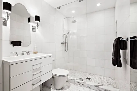 a bathroom with a toilet a sink a mirror and shower