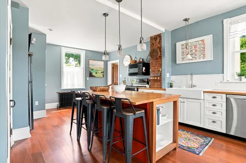 a open kitchen with stainless steel appliances granite countertop a sink a stove a refrigerator and island with wooden floor