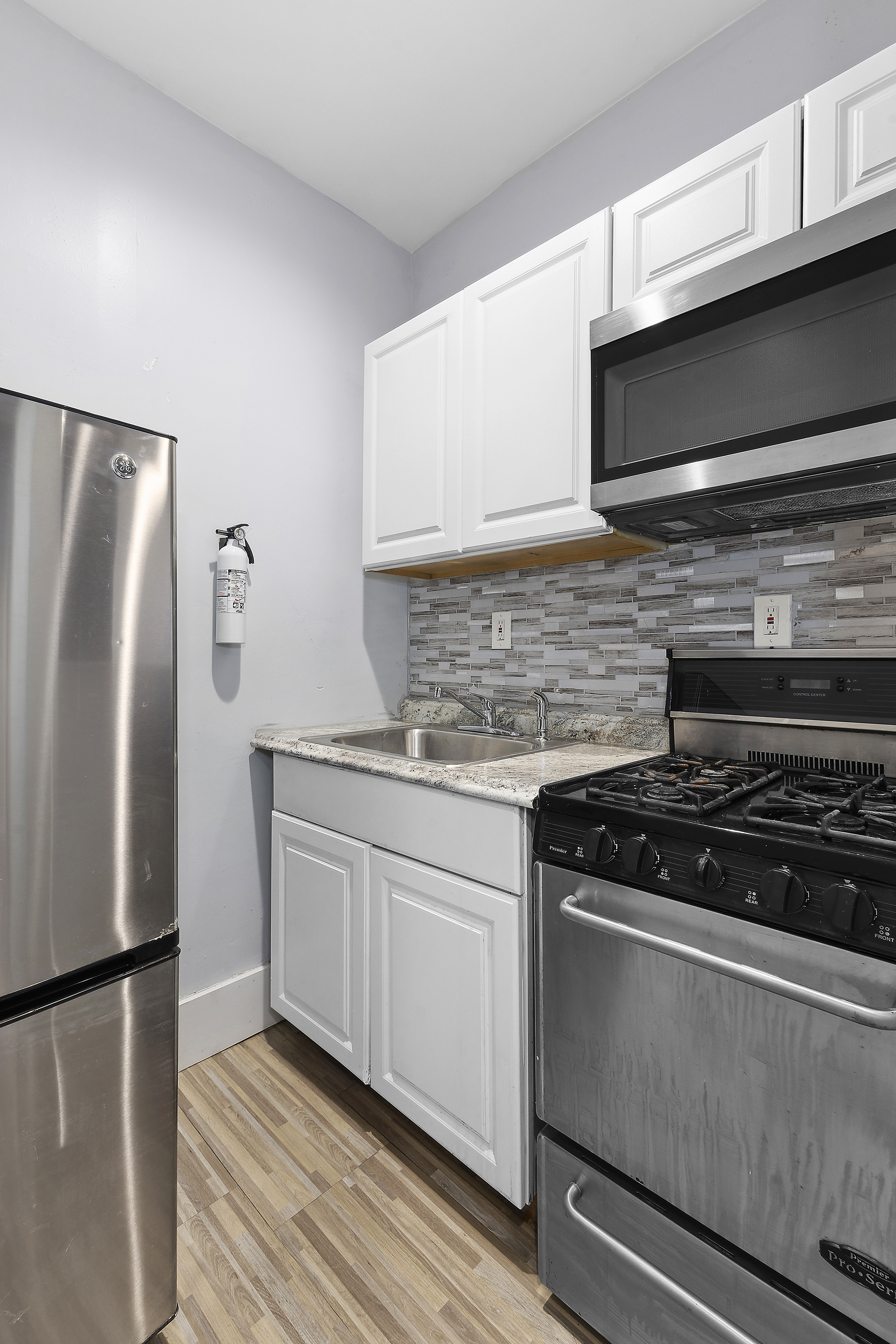 693 MacDonough Street, Unit 2 Brooklyn, NY 11233 - Photo 6 of 11 a kitchen with granite countertop a refrigerator stove and microwave
