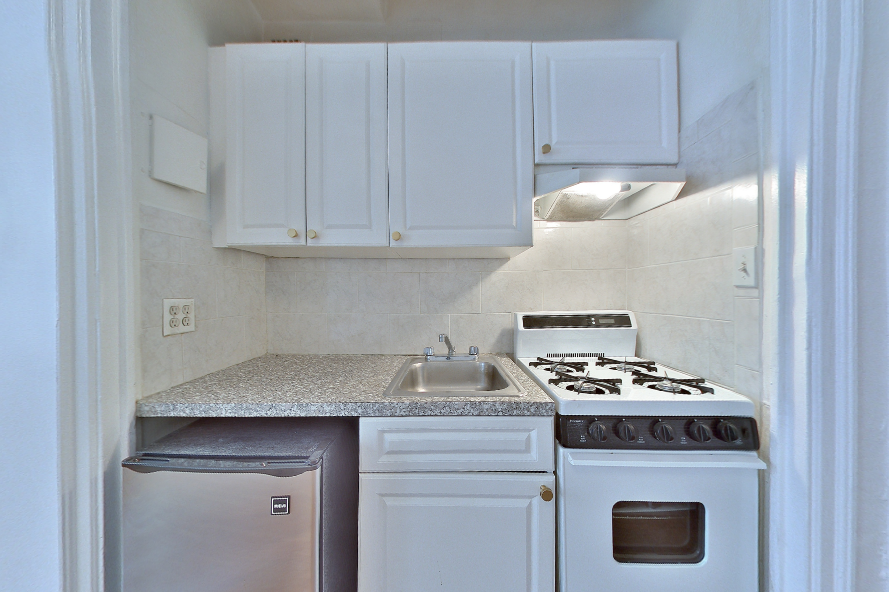 457 West 57th Street, Unit 814 Manhattan, NY 10019 - Photo 3 of 5 a kitchen with granite countertop a sink a stove and cabinets