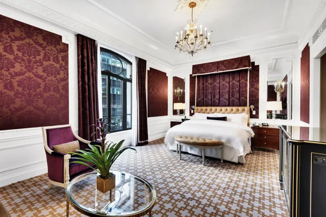 a spacious bedroom with a large bed and a chandelier