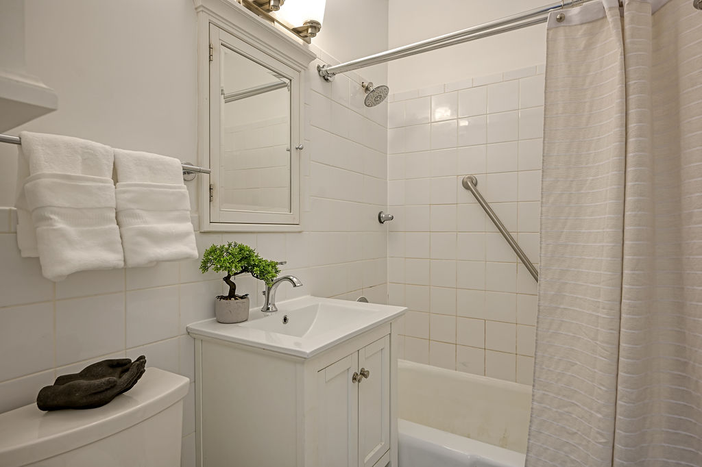 300 East 74th Street, Unit 6D Manhattan, NY 10021 - Photo 10 of 12 a bathroom with a sink a mirror and a shower