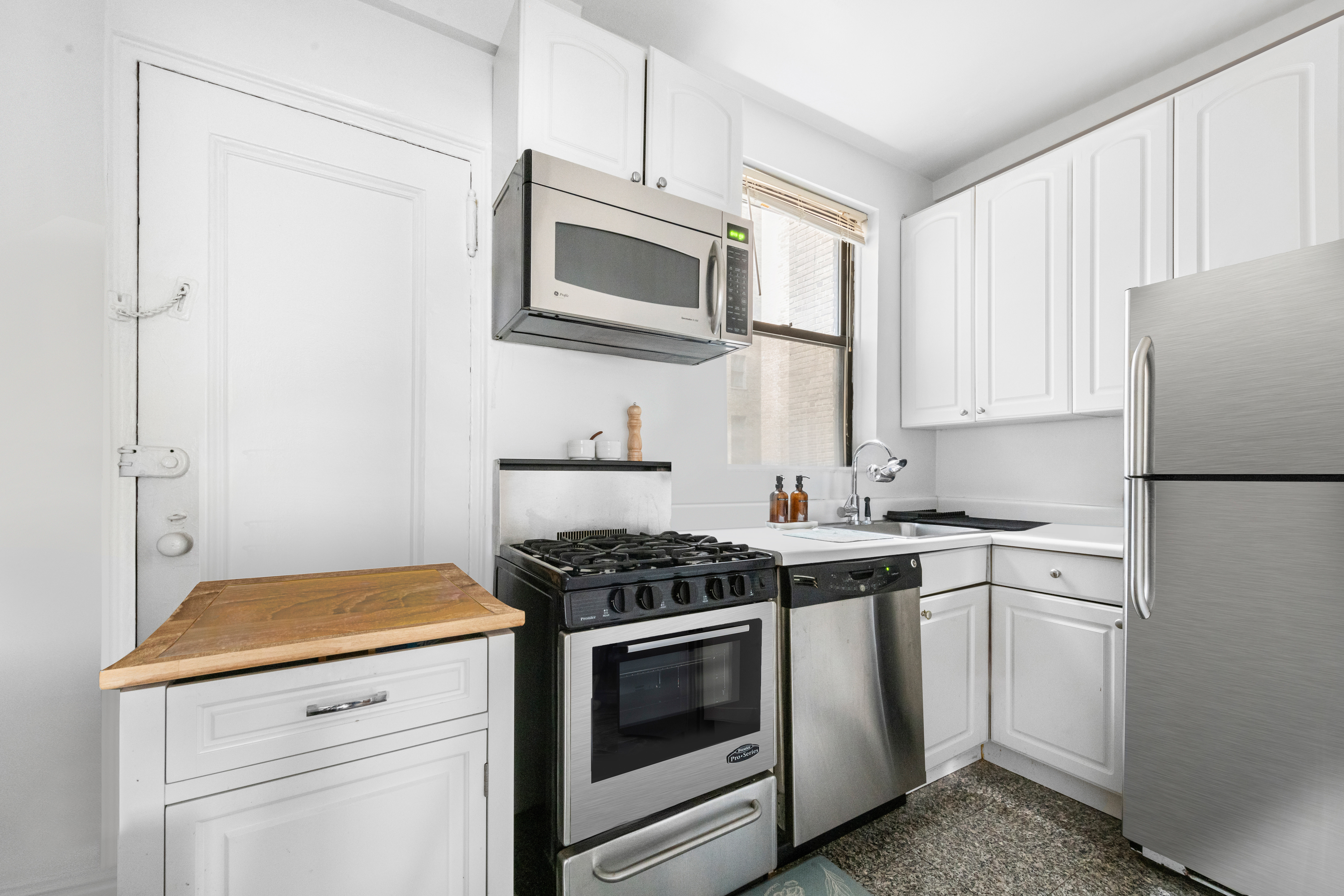 142 East 49th Street, Unit 7B Manhattan, NY 10017 - Photo 5 of 11 a kitchen with stainless steel appliances a stove microwave and refrigerator
