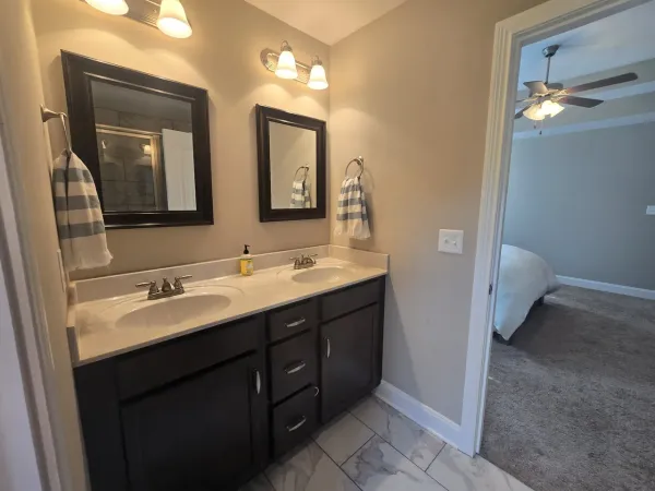a bathroom with a double vanity sink and mirror with toilet