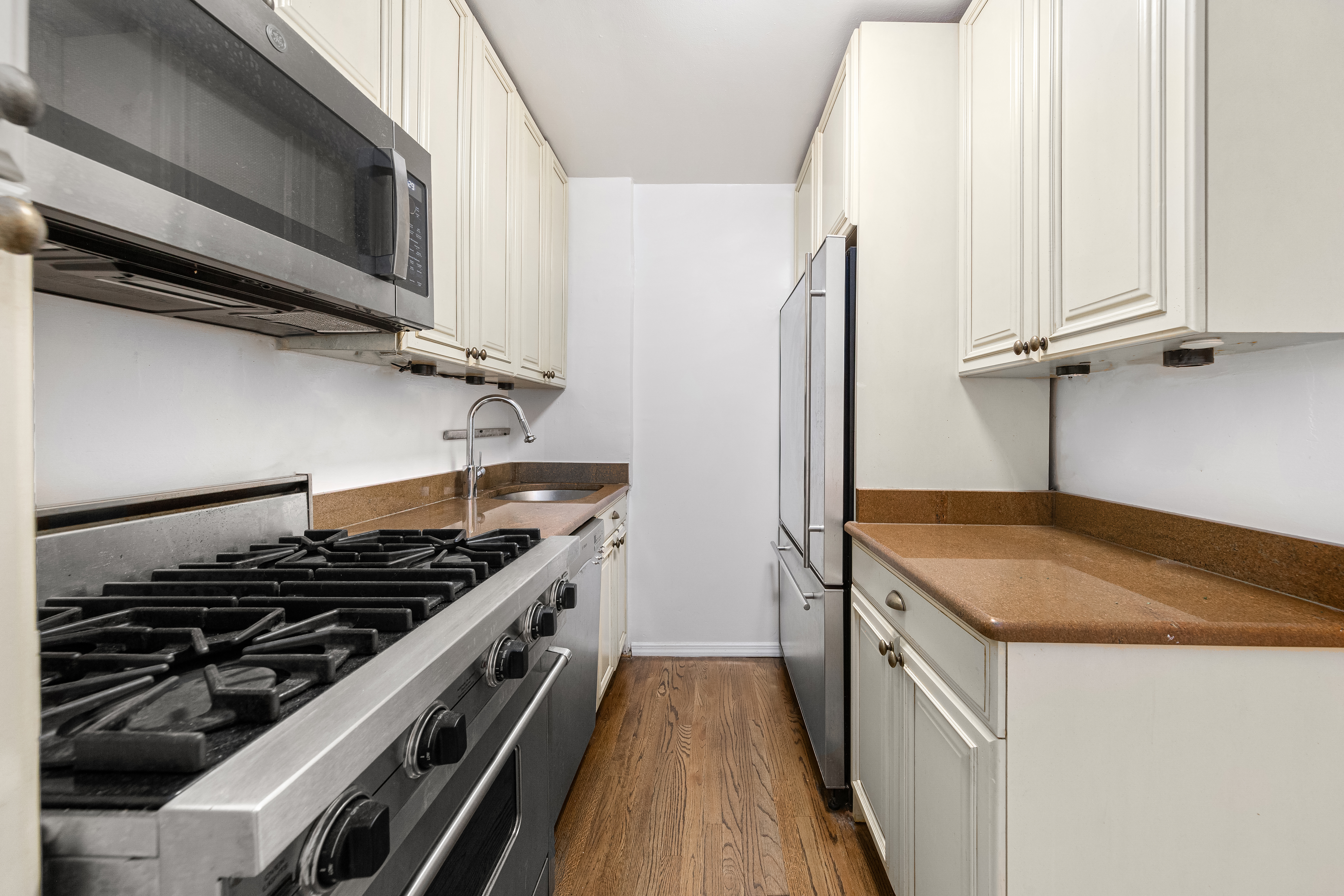 140 7th Avenue, Unit 4M Manhattan, NY 10011 - Photo 5 of 7 a kitchen with granite countertop a sink stove and refrigerator