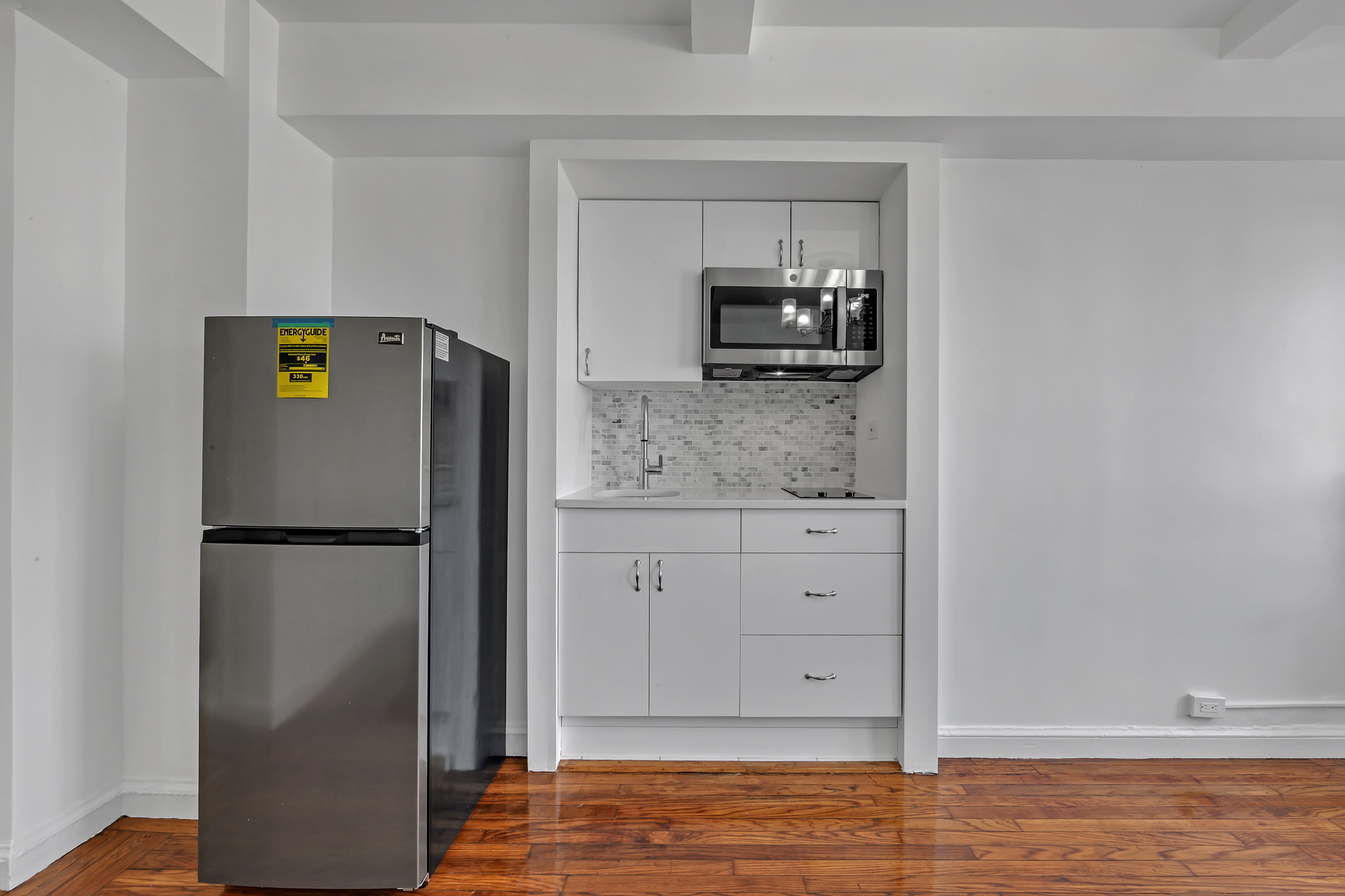 25 Tudor City Place, Unit 1202 Manhattan, NY 10017 - Photo 7 of 19 a kitchen with a refrigerator a stove and a sink