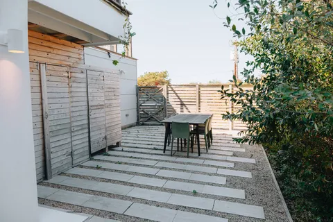 a view of a patio with table and chairs with wooden floor and fence