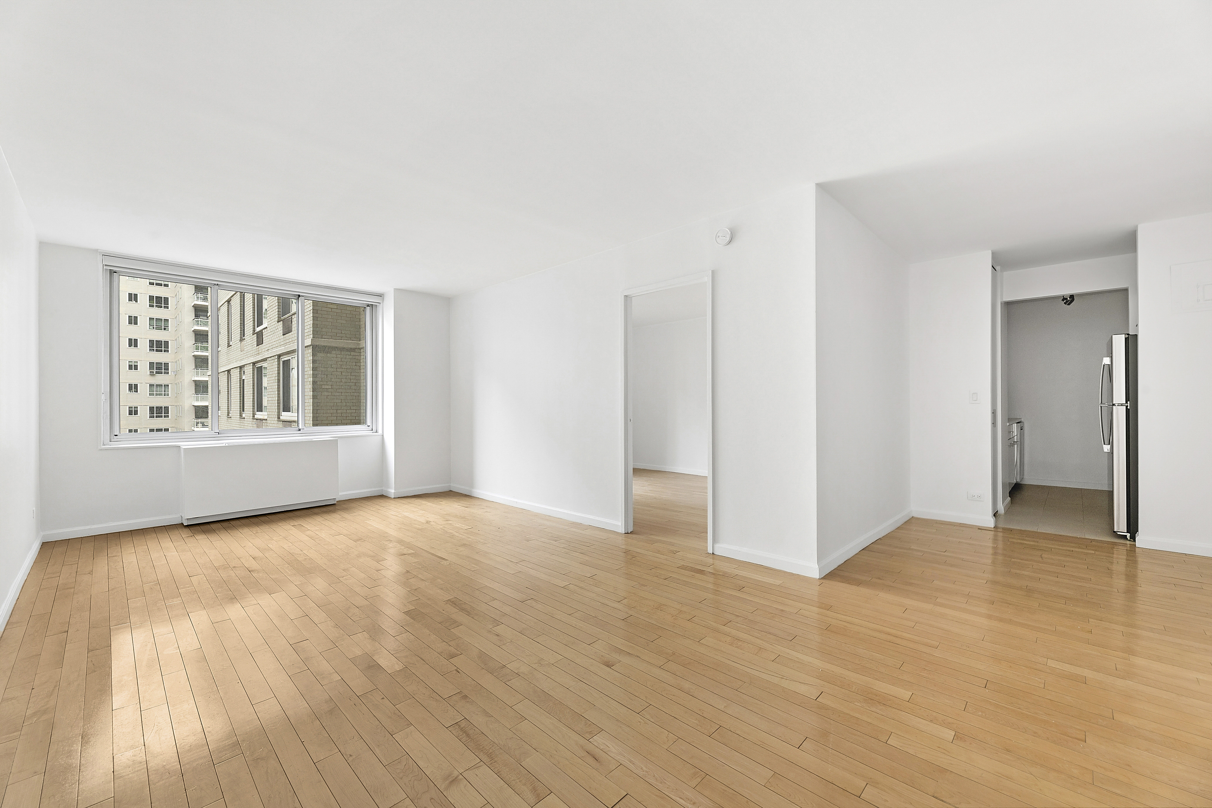 220 East 65th Street, Unit 8J Manhattan, NY 10065 - Photo 2 of 13 a view of an empty room with wooden floor and a window