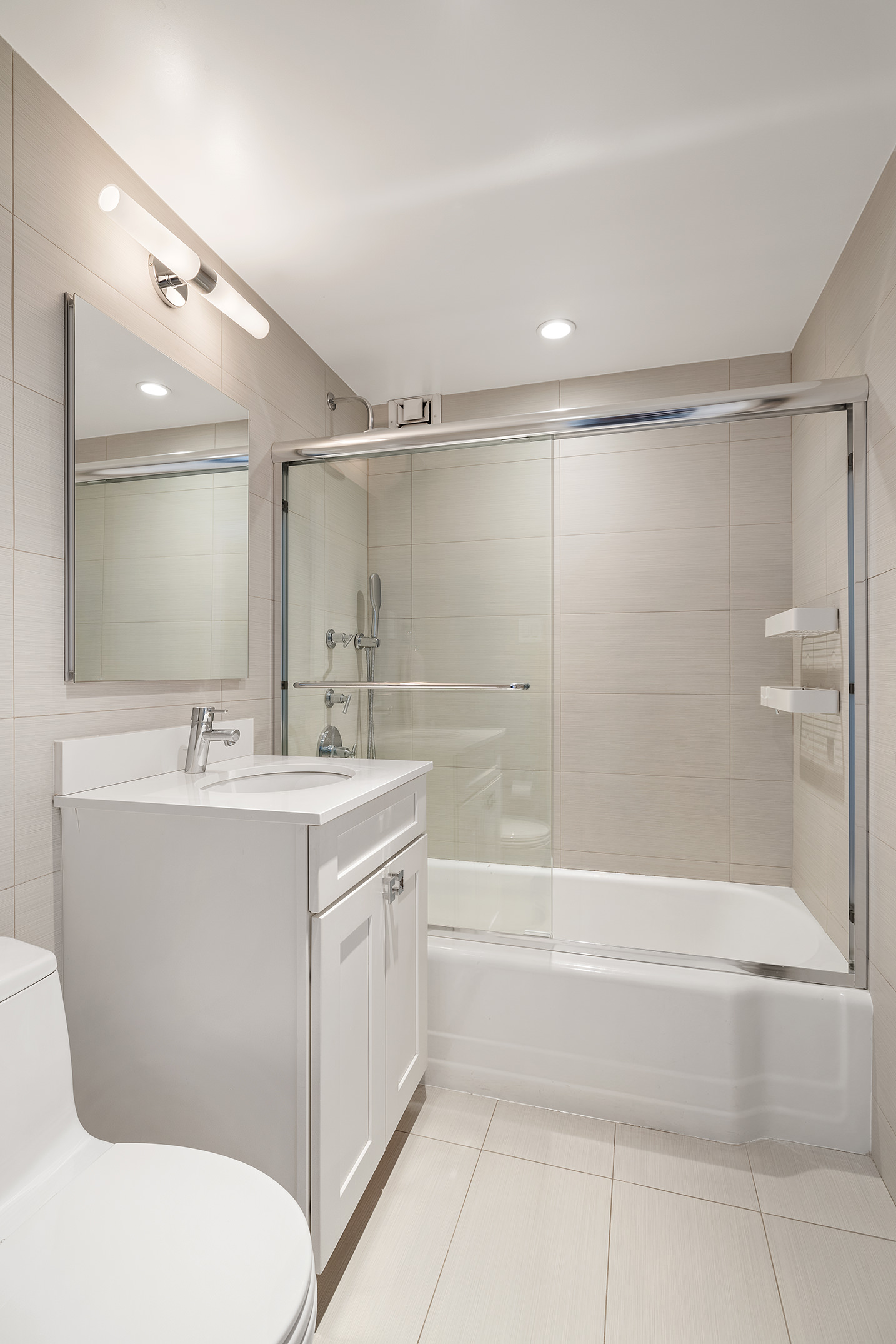 136 East 76th Street, Unit 16DE Manhattan, NY 10021 - Photo 11 of 14 a bathroom with a sink mirror toilet and bathtub