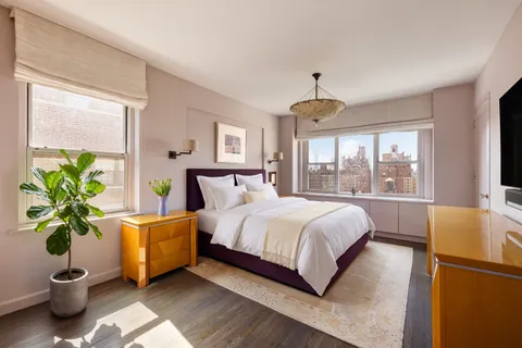 a bed sitting in a spacious bedroom next to a window