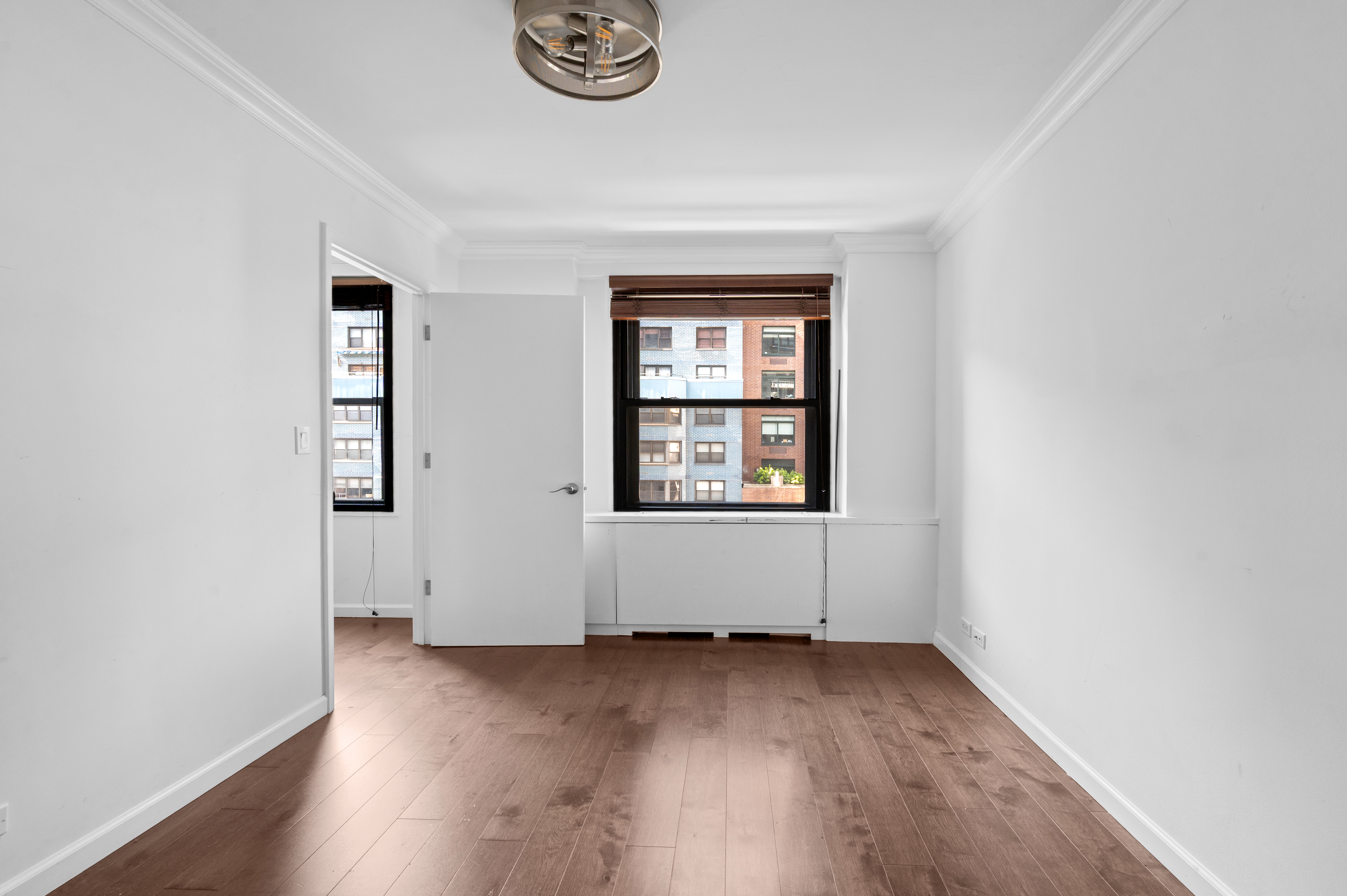 225 East 57th Street, Unit 14F Manhattan, NY 10022 - Photo 12 of 14 an empty room with wooden floor and windows