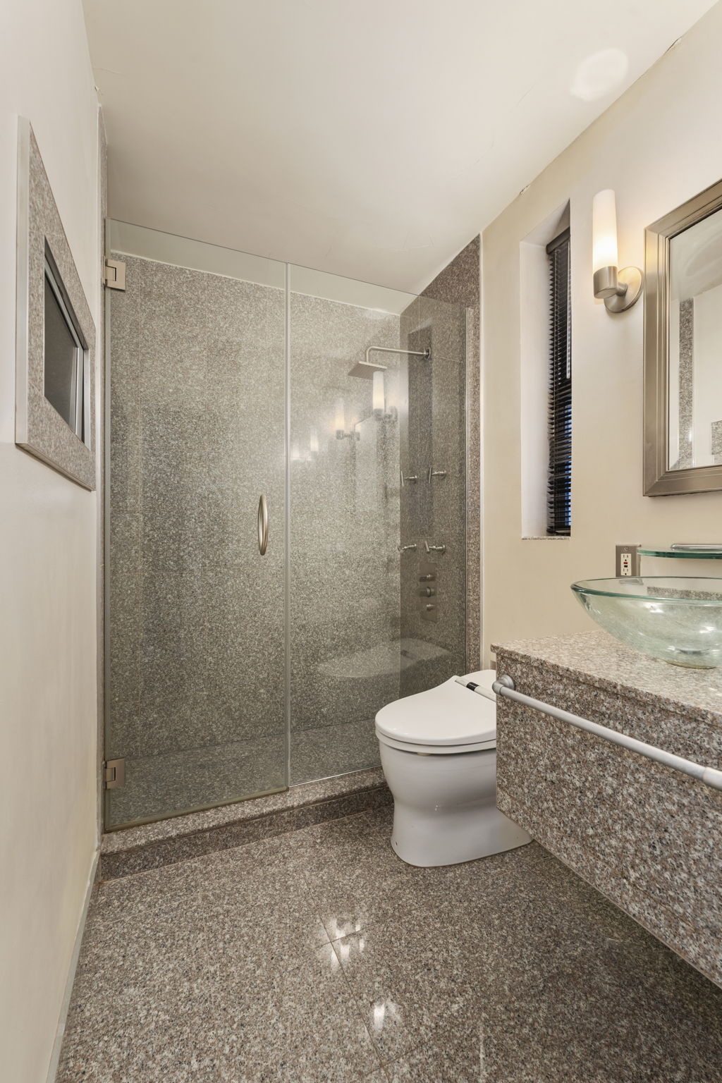 230 Central Park South, Unit 8F Manhattan, NY 10019 - Photo 6 of 7 a bathroom with a granite countertop toilet a sink a mirror and shower