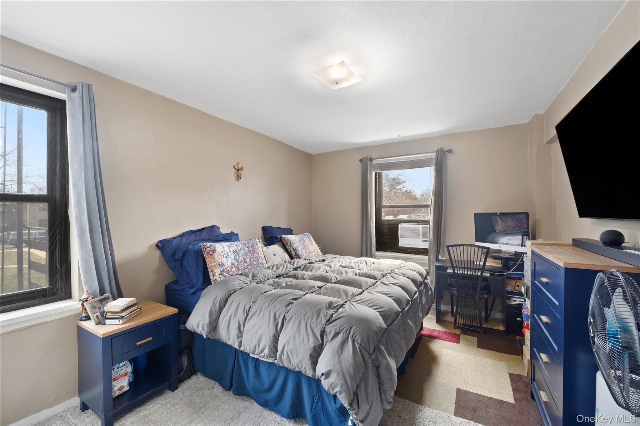 73-11 Bell Boulevard, Unit 2C Queens, NY 11364 - Photo 3 of 16 a bedroom with a bed and a flat tv screen on the dresser