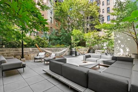 a view of a patio with couches and chairs with potted plants and large trees