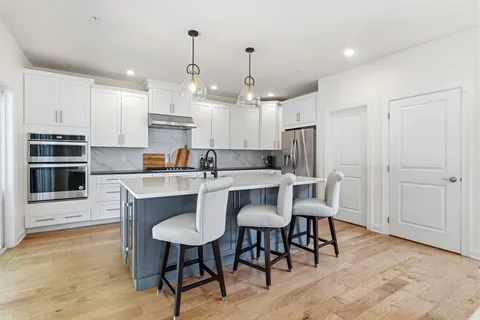 a kitchen with kitchen island a dining table chairs stainless steel appliances and cabinets