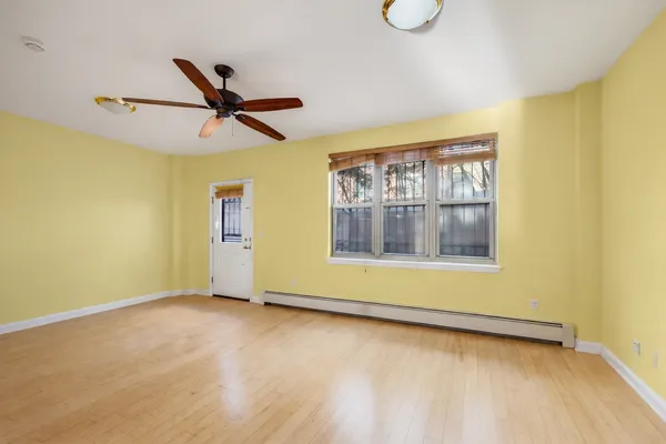 a view of an empty room with wooden floor and a window