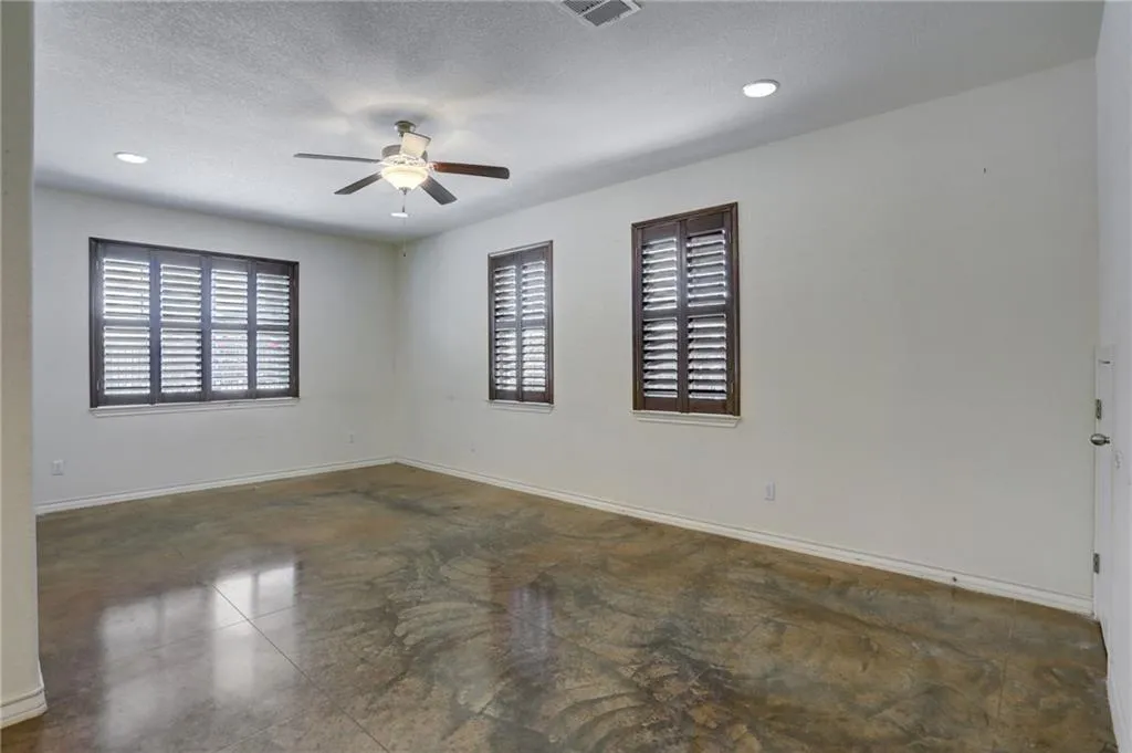 en empty room with windows and ceiling fan