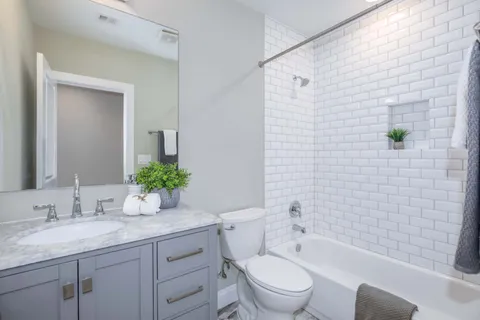 a bathroom with a granite countertop toilet a sink a mirror a shower and a bathtub