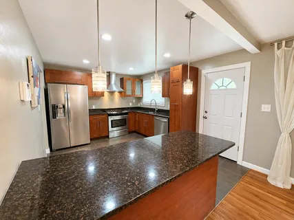 a kitchen with stainless steel appliances granite countertop a refrigerator a sink a stove and island