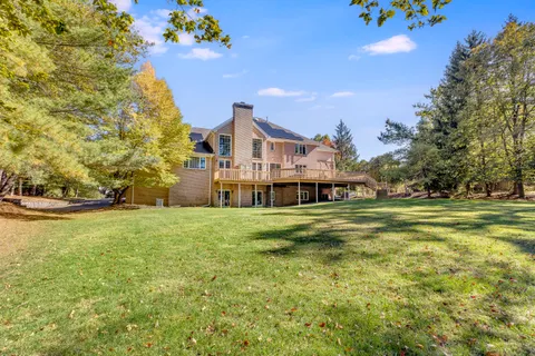 a view of a big house with a big yard and large trees