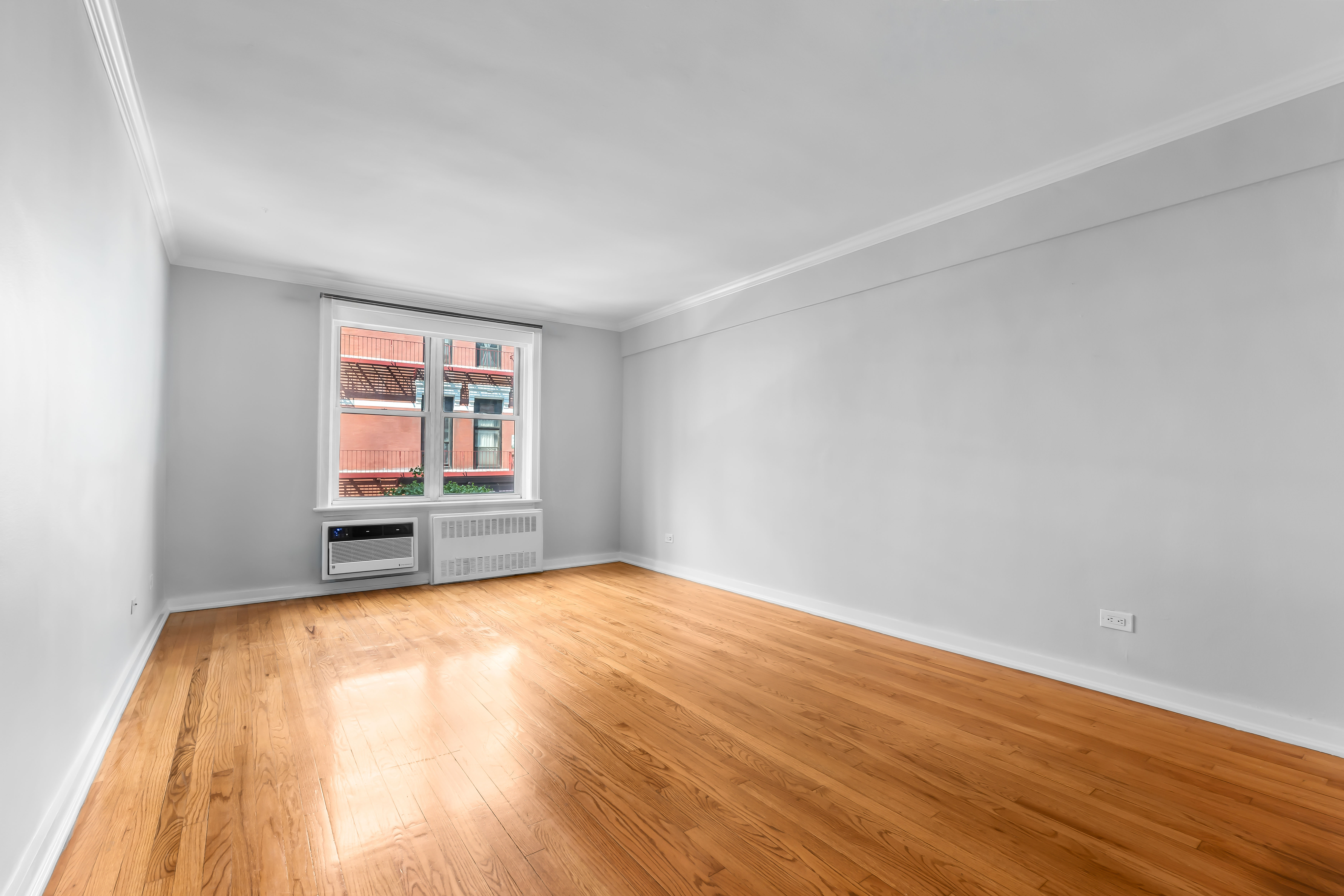 88 Bleecker Street, Unit 2M Manhattan, NY 10012 - Photo 2 of 14 a view of an empty room with wooden floor and a window