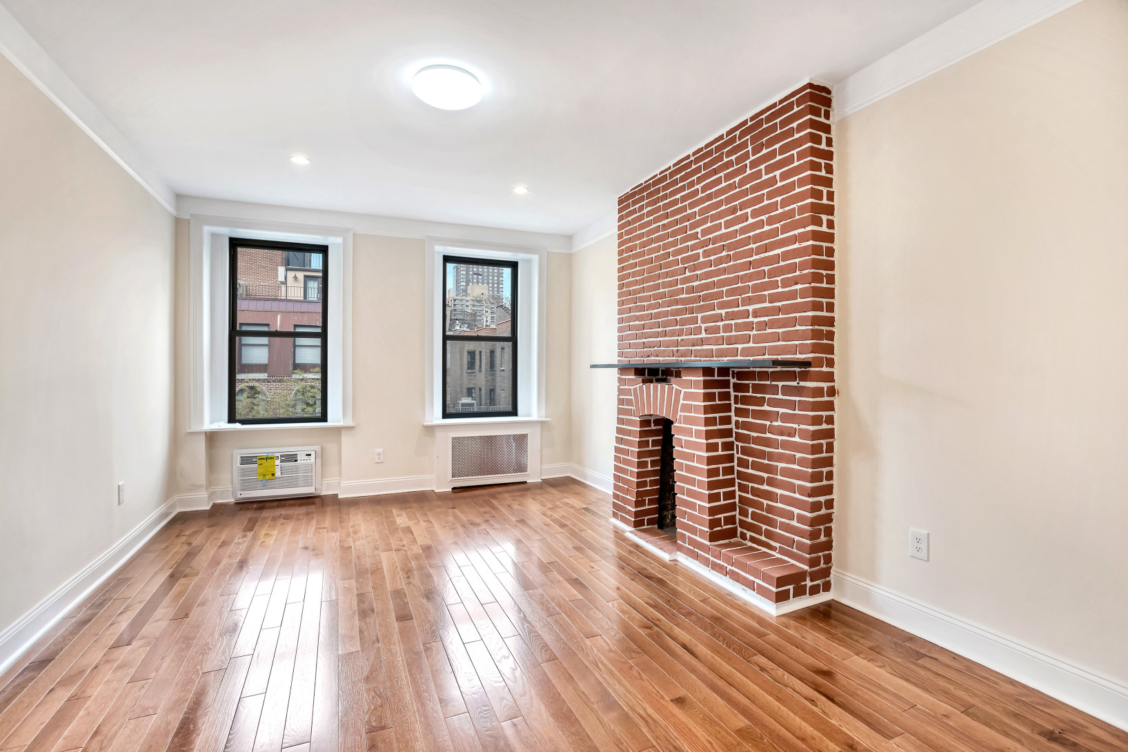 314 East 83rd Street, Unit 5W Manhattan, NY 10028 - Photo 3 of 4 an empty room with wooden floor and windows