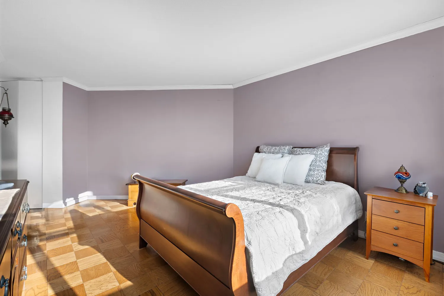 a bedroom with a bed and a lamp on the dresser