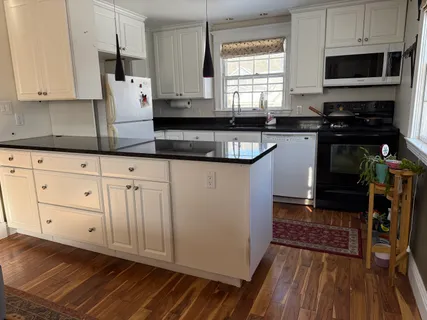 a kitchen with granite countertop a sink a stove and refrigerator