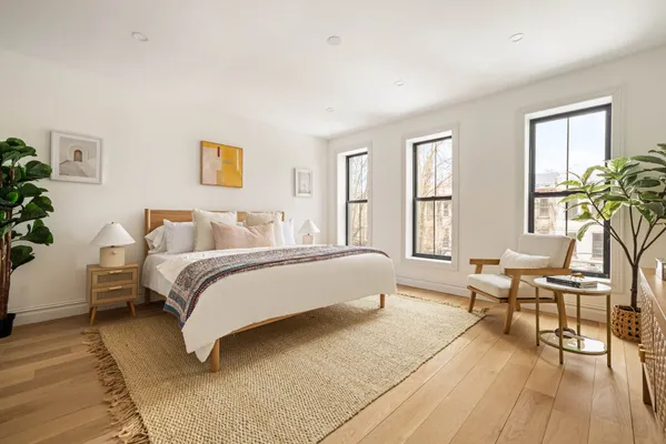 a spacious bedroom with a bed and wooden floor