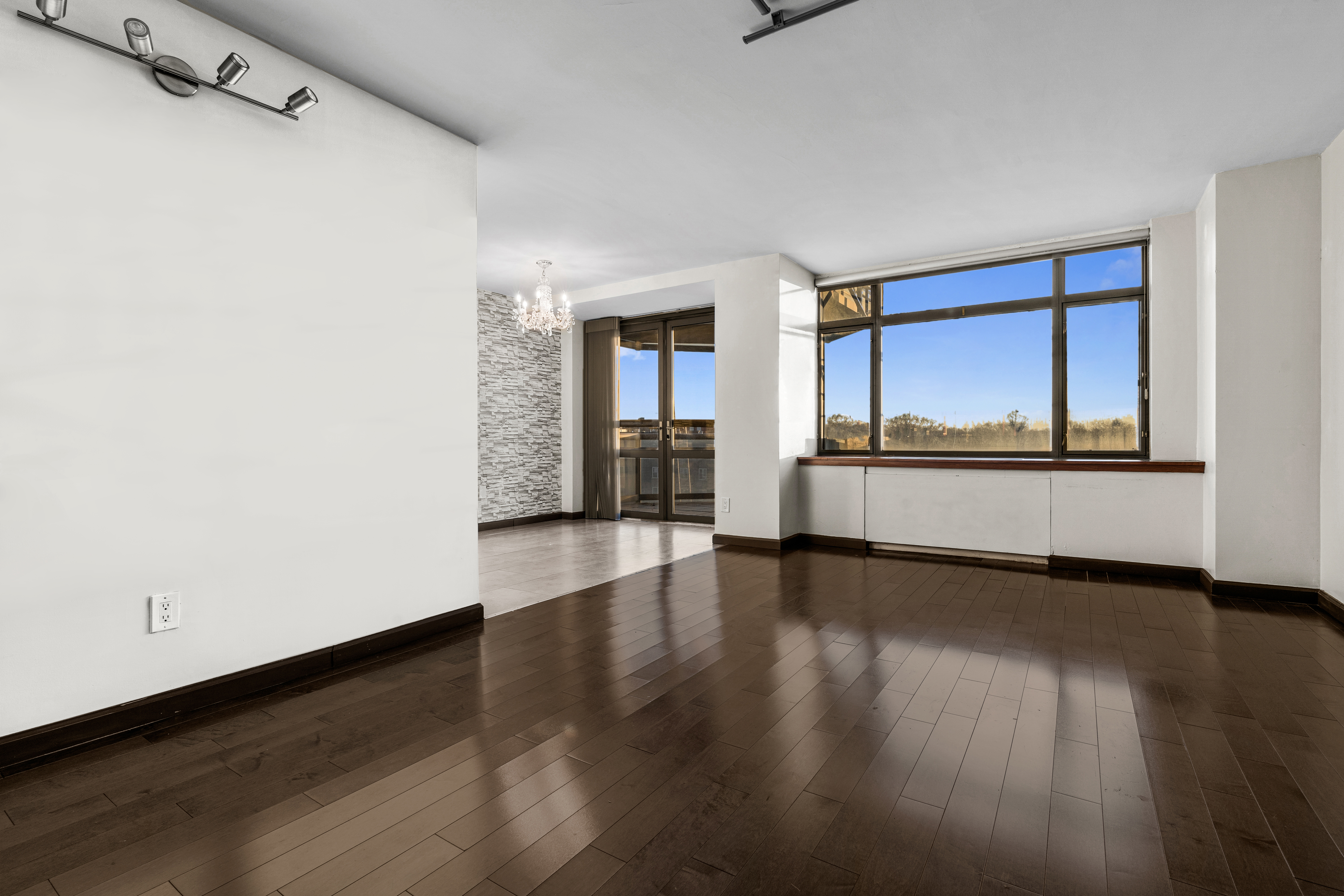 112-01 Queens Boulevard, Unit 7E Queens, NY 11375 - Photo 10 of 27 an empty room with wooden floor and windows