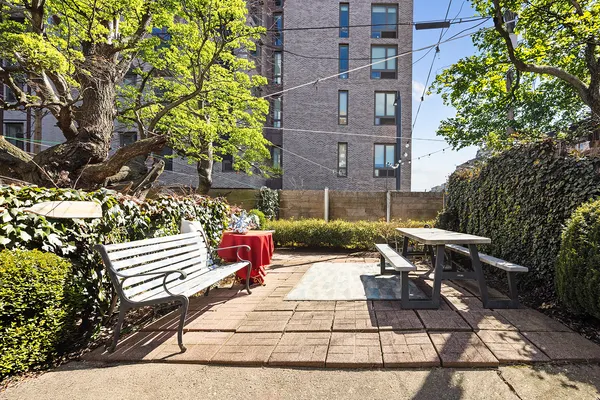 a view of a patio with couches and table and chairs with wooden fence and plants