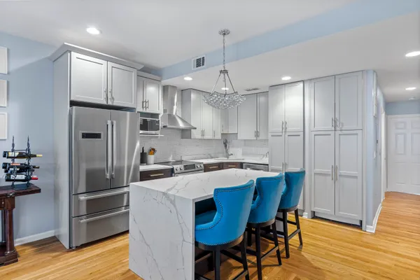 a kitchen with stainless steel appliances a refrigerator a stove a sink a dining table and chairs with wooden floor