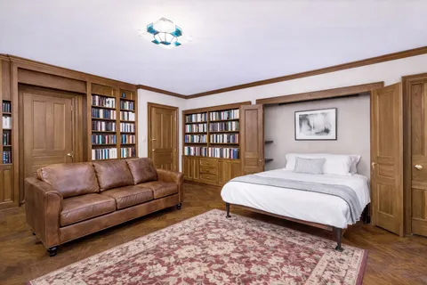 a spacious bedroom with a bed a couch and a bookshelf