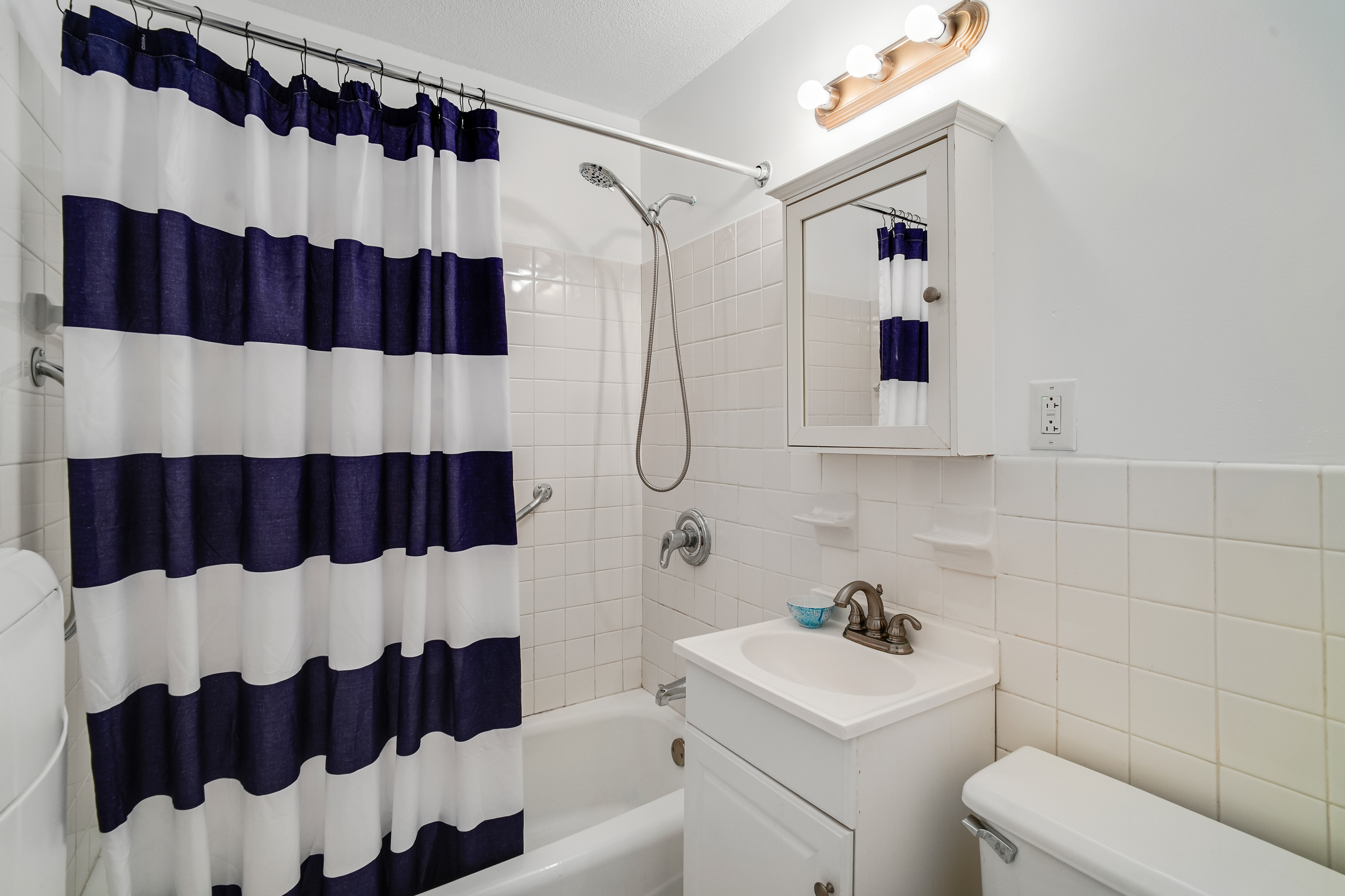290 West 232nd Street, Unit 18B Bronx, NY 10463 - Photo 10 of 16 a bathroom with a sink and a shower curtain