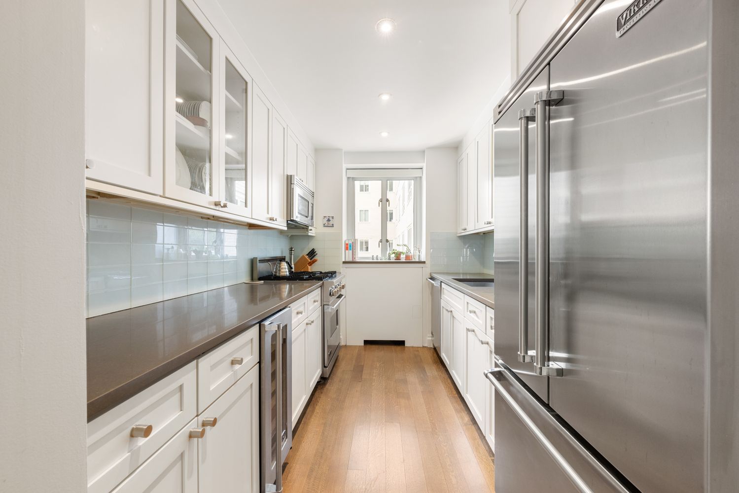 a kitchen with granite countertop a refrigerator and white cabinets
