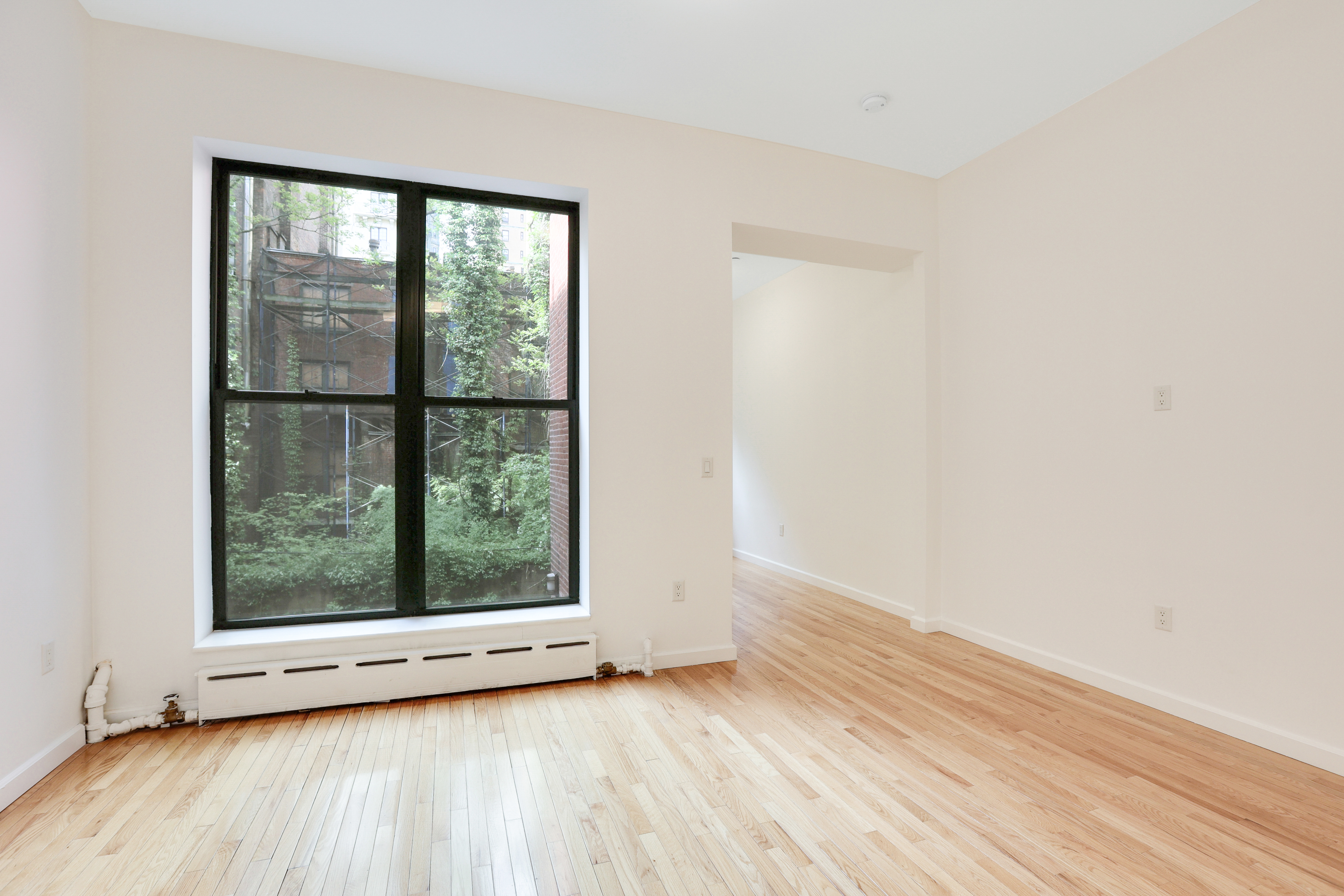 230 West 75th Street, Unit 1 Manhattan, NY 10023 - Photo 3 of 9 an empty room with wooden floor and window
