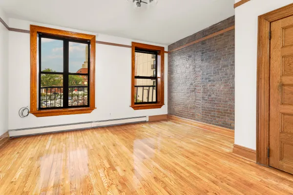 a view of an empty room with window and wooden floor