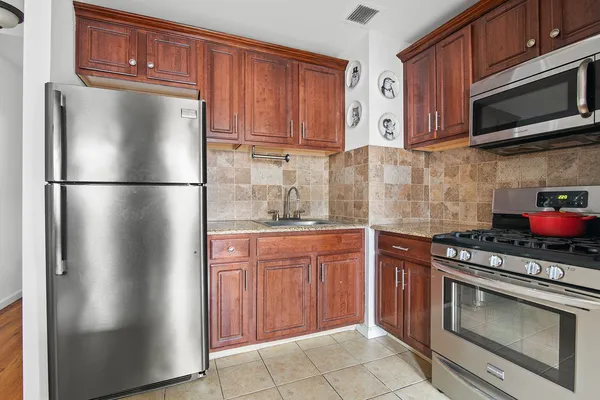 a kitchen with stainless steel appliances granite countertop a refrigerator stove a sink dishwasher and microwave oven