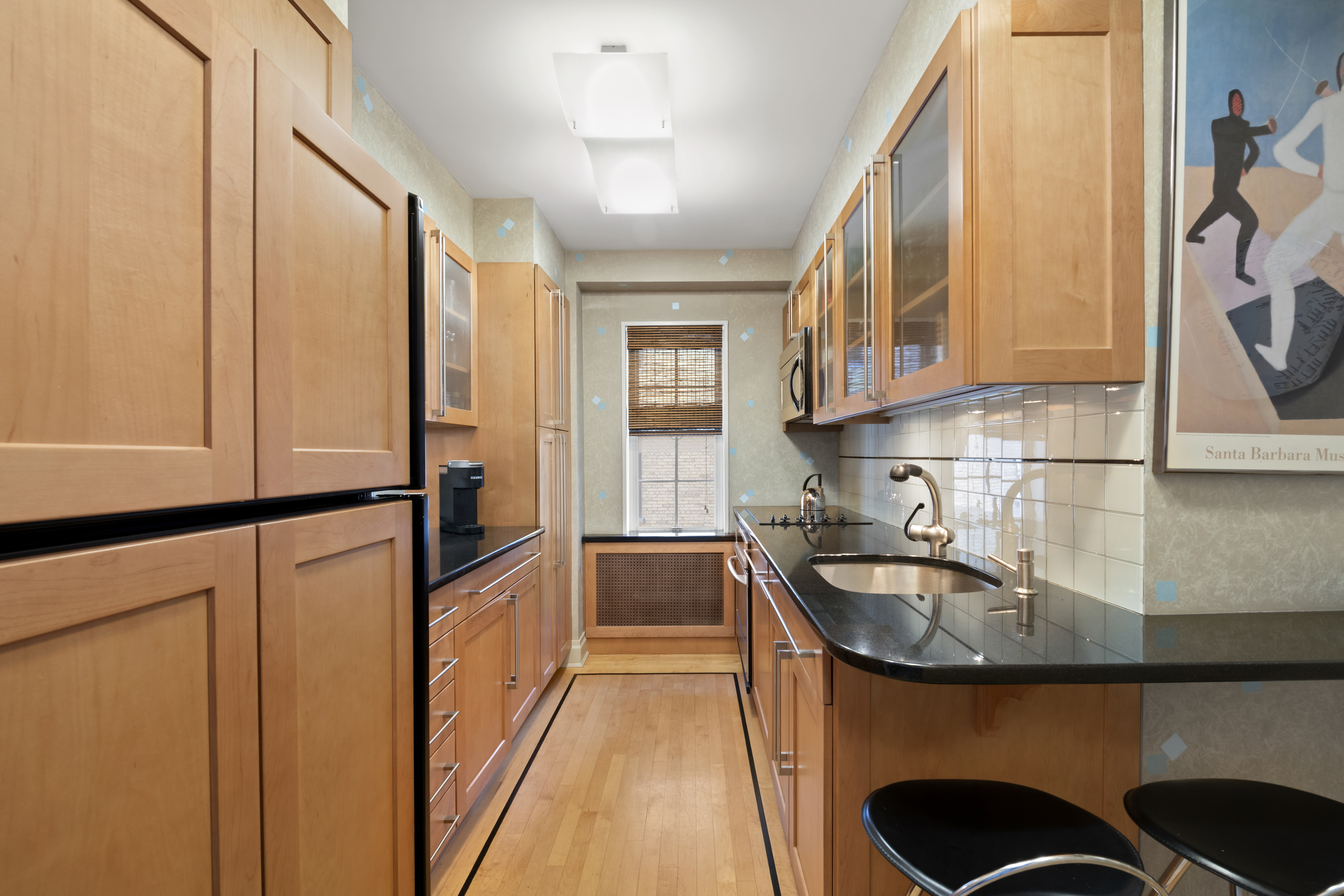 1065 Park Avenue, Unit 11A Manhattan, NY 10128 - Photo 5 of 14 a kitchen with sink a refrigerator and cabinets