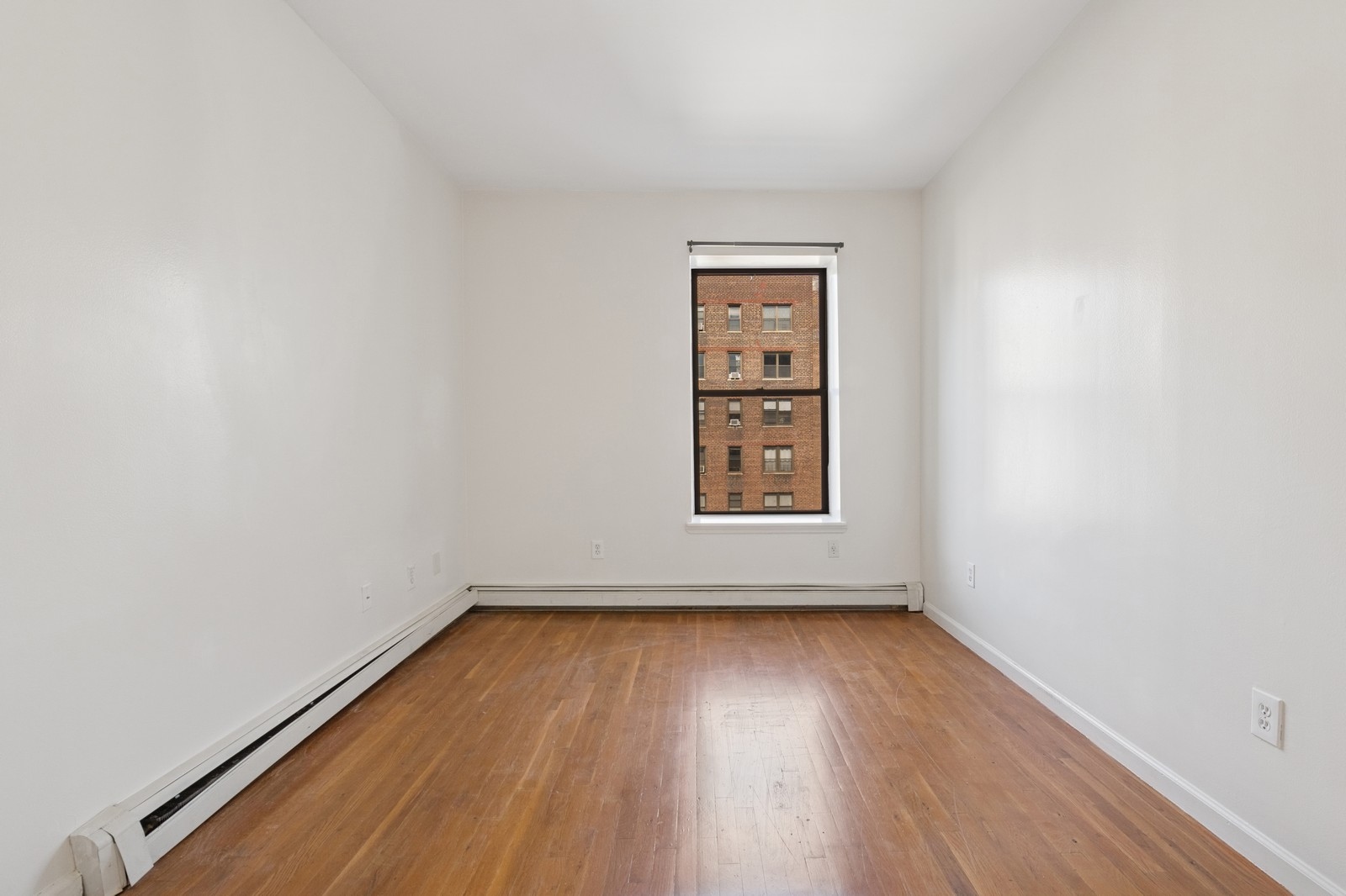 859 Riverside Drive, Unit 3 Manhattan, NY 10032 - Photo 5 of 7 an empty room with wooden floor and windows