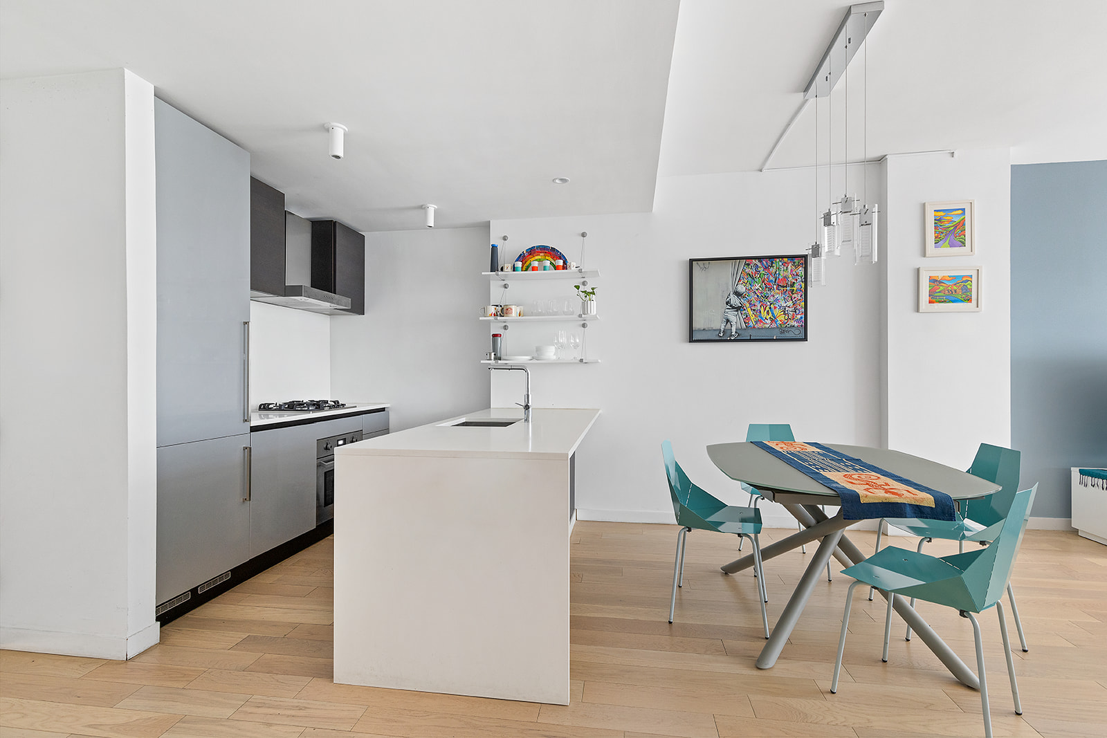 540 West 49th Street, Unit 108N Manhattan, NY 10019 - Photo 2 of 5 a kitchen with stainless steel appliances a refrigerator a stove a dining table and chairs with wooden floor
